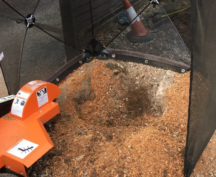 Stump grinding in progress with wood chippings around the stump